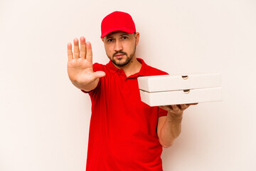 Young delivery man holding pizzas isolated on beige background standing with outstretched hand...