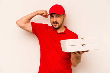 Young delivery man holding pizzas isolated on beige background raising fist after a victory, winner concept.