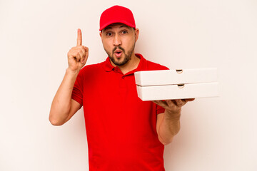 Young delivery man holding pizzas isolated on beige background having some great idea, concept of creativity.