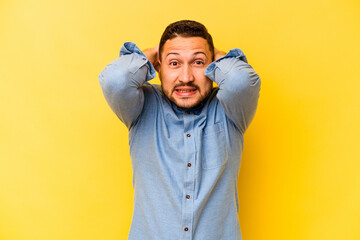 Young hispanic man isolated on yellow background screaming with rage.