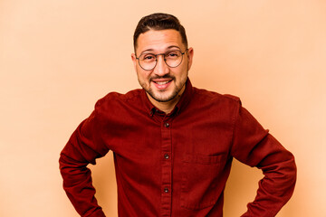 Young hispanic man isolated on beige background confident keeping hands on hips.