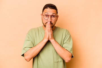 Young hispanic man isolated on beige background shocked covering mouth with hands.