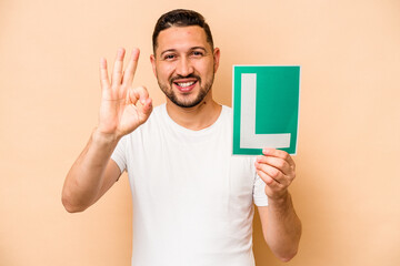 Hispanic man holding a beginner driver sign isolated on beige background
