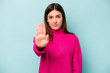 Fototapeta premium Young caucasian woman isolated on blue background standing with outstretched hand showing stop sign, preventing you.