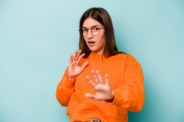 Young caucasian woman isolated on blue background being shocked due to an imminent danger