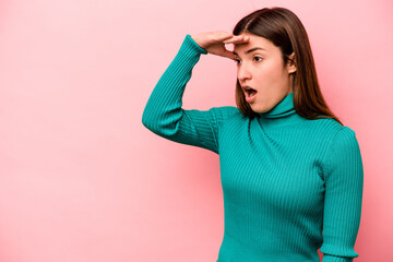 Young caucasian woman isolated on pink background looking far away keeping hand on forehead.