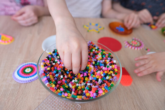 close-up of children's hands creating perler bead patterns, make crafts using thermomosaic technique, beading patterns, perler bead art, concept development of fine motor skills, thermo mosaic ideas