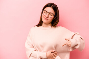 Young caucasian woman isolated on pink background having a liver pain, stomach ache.