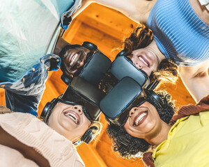 Portrait from below of a team of online players with augmented reality headset, four people of...
