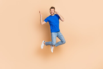 Fototapeta na wymiar Full length photo of young man jump up tell listen talk mobile communication energetic isolated over beige color background