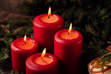 Obraz na płótnie Canvas four burning Red advent candles in advent wreath decoration on wooden dark background. tradition in time before Christmas. xmas lights with christmas fir deco background concept. Festive still life.