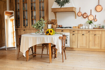 Stylish dining room with furniture in retro style. Cozy Wooden cuisine  decorated with summer decor.  Kitchen utensils, dishes, plates. Interior design scandinavian kitchen with round table and chairs