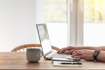 person using laptop computer at wooden table, working from home concept