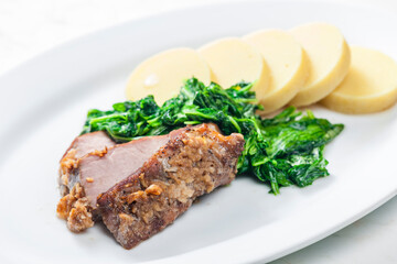 pork meat with garlic served with spinach and potato dumplings