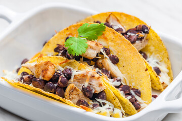 tacos filled with grilled chicken meat, red beans and grated cheese
