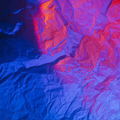 Abstract background with crumpled paper in neon gradient. Vivid blue, pink and orange colors