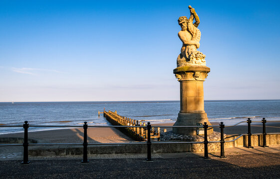 Statue of Neptune fighting a serpent on the seafront of Lowestoft in Suffolk east Anglia England, with the may sun setting