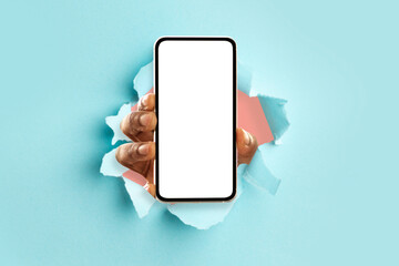 Black person showing white empty smartphone screen breaking through paper