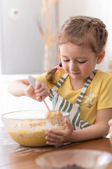 Happy child playing with flour in kitchen. kid cooking food. little cute girl in apron in preparing dough, baking pie, oatmeal cookies, making biscuit