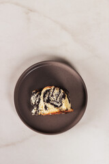 Piece of poppy seed cake on a plate on a marble background, closeup 