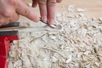 Selbst geschnitzter Holzlöffel eingespannt im Schraubstock bearbeitet mit Messer Werkzeug auf...