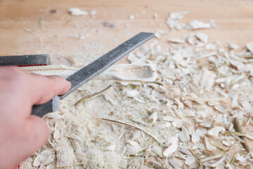 Selbst geschnitzter Holzlöffel eingespannt im Schraubstock bearbeitet mit Holzraspel Raspel auf einer Werkbank mit Holzspäne, Deutschland