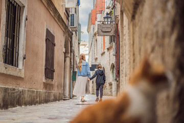 Mom and son travelers enjoying Colorful street in Old town of Kotor on a sunny day, Montenegro. Travel to Montenegro concept