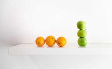 Green apples and oranges on a white background close-up.