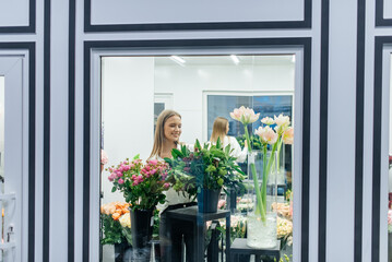 A young girl poses with a beautiful festive bouquet against the background of a cozy flower shop. Floristry and bouquet making in a flower shop. Small business.