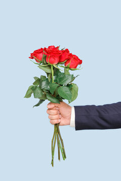 A man's hand holds a beautiful bouquet of red roses, vertical photo