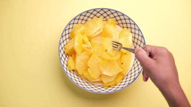 slice of pineapple in bowl on yellow background 