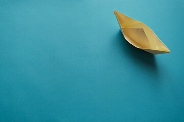 Yellow paper origami boat on blue background