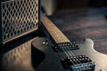 Close-up, black electric guitar on a dark background.