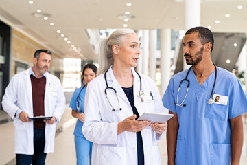Mature doctor and mixed race nurse discussing patient case at hospital