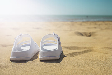 Summer holiday concept. Pair of sandals on the beach.