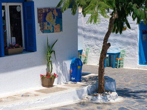 Schinoussa Island, Greek Islands, Greece: 23 July 2021 - Cycladic Panagia village street view, white buldings, blue windows and doors wooden, stone roads, blue bright summer sky