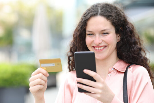 Happy woman buying on line with credit card and cell phone
