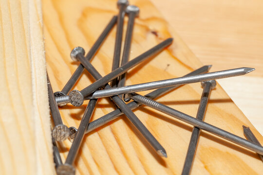 yellow-orange pine wood board and steel nails during construction work