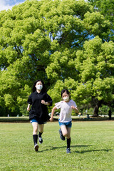 Obraz premium 初夏の公園で元気で遊んでいる子供姉妹の姿