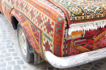 Close up view of headlight vintage car cover into traditional old carpet. For rent car.