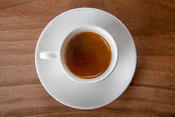 White cup of espresso on wooden background, top view	