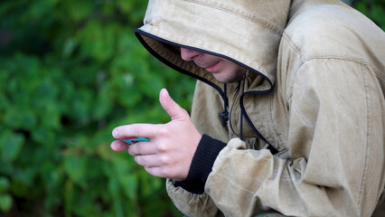 Busy young environmentalist is working on the phone in the woods. Young man sitting in the woods with the phone