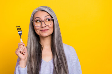 Portrait of charming adorable starving grandmother choose dish from menu isolated on yellow color background