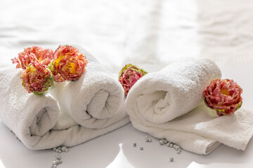 Obraz na płótnie Canvas Close-up, white terry bath towels and flowers.
