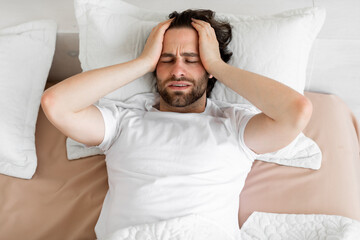 Restless young man waking up with headache