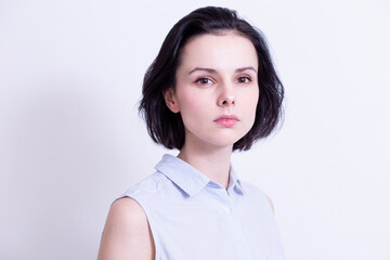 woman in a blue sleeveless office shirt, light background