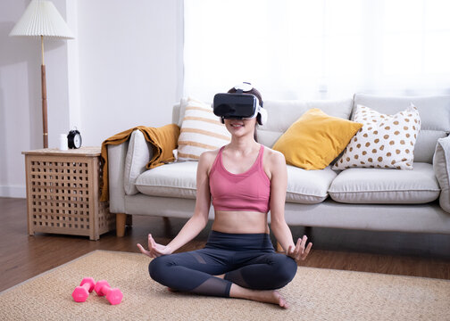 Beautiful woman in virtual reality glasses makes yoga and aerobics remotely.Girl Future technology concept.Modern imaging technology.Classes in single sports remotely.Young Female smile meditation.