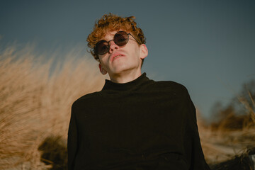 portrait of a modern young man in round sunglasses