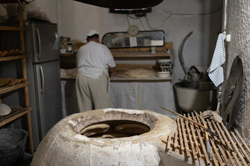 Caucasian man near tandoor in kitchen at bakery. Stone oven for baking tasty bread. Adult man in...