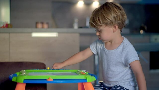 Little boy plays with magnetic drawing board